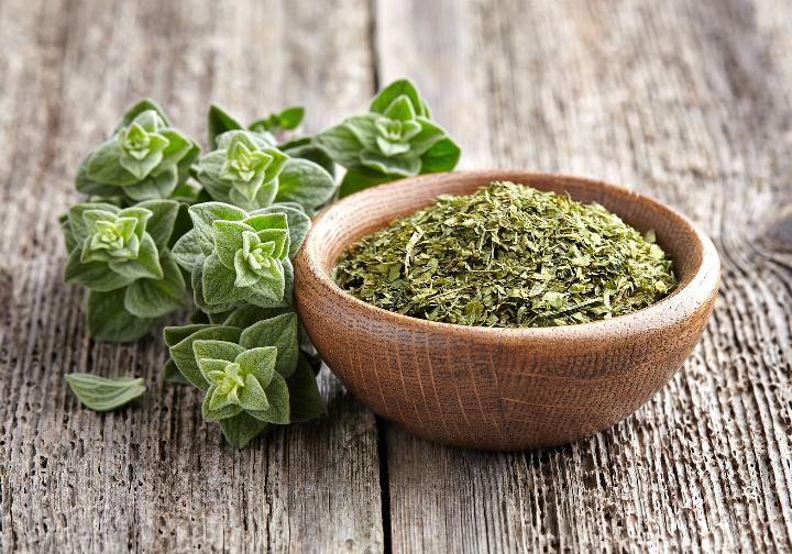 Oregano in a bowl on a wooden table. Oregano in a bowl on a wooden table.