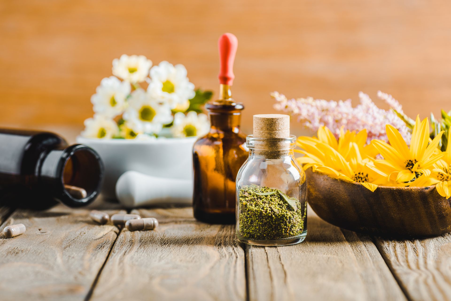Spices in bottles, bowls of flowers on a wooden table. Alternative Health options. Spices in bottles, bowls of flowers on a wooden table.Alternative Health Options.